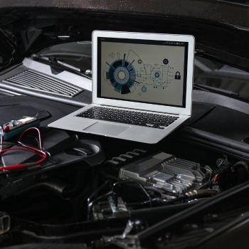 Laptop displaying diagnostic software on car engine, highlighting automotive diagnostics services offered by Asher Auto Care in Dallas, TX.
