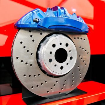 Brake caliper and rotor assembly with drilled disc, showcasing blue caliper, emphasizing brake repair services at Asher Auto Care in Dallas, TX.