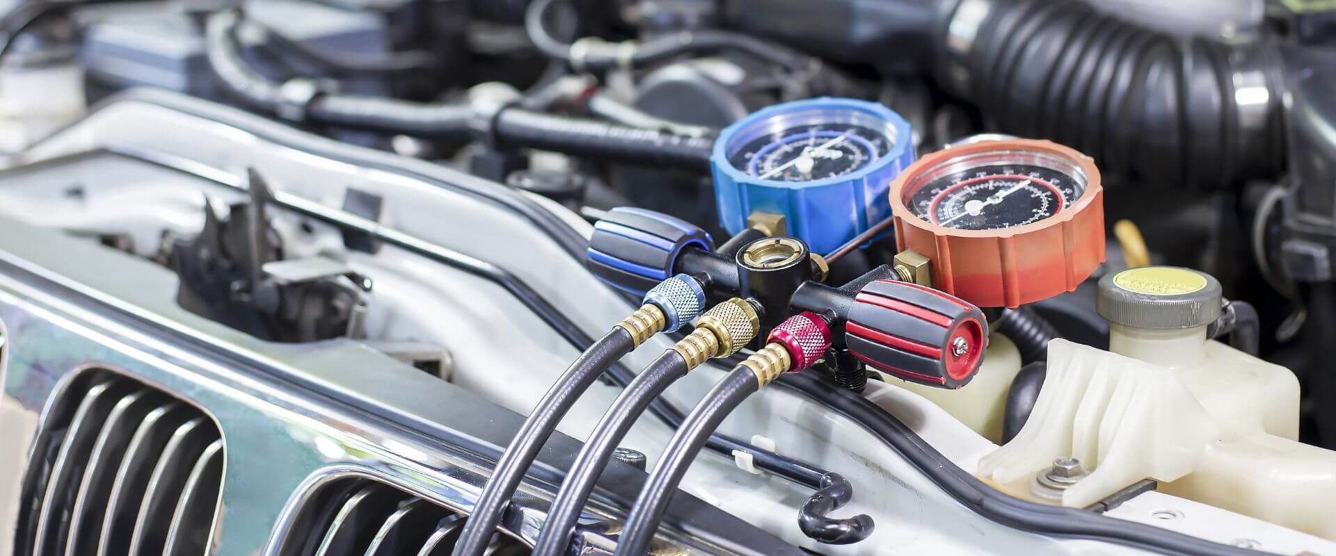 Automotive AC repair gauges on a vehicle's engine, highlighting diagnostic tools for air conditioning system issues in Dallas, TX.