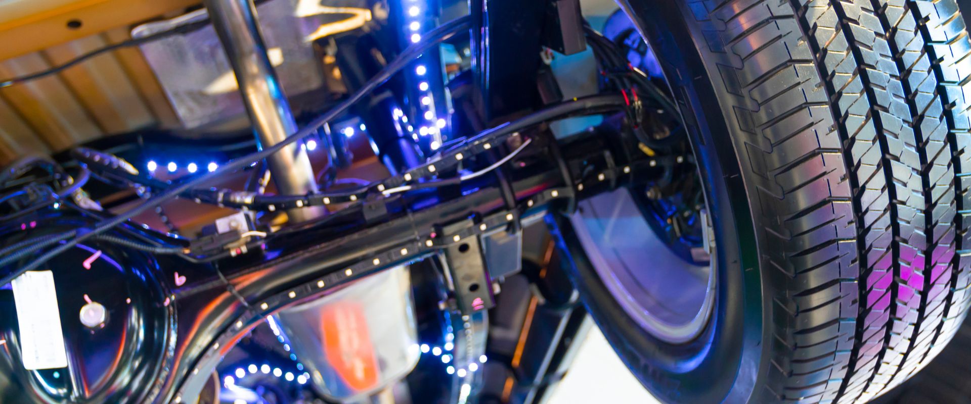 Drivetrain and differential components with illuminated wiring and a close-up view of a tire, relevant to drivetrain and differential repair services in Dallas, TX.