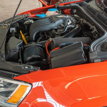 Engine compartment of a red vehicle showcasing essential components for maintenance, emphasizing the importance of preventative care and engine repair services at Asher Auto Care in Dallas, TX.
