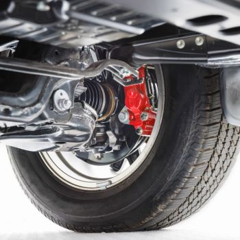 Close-up of a car's suspension system and red brake caliper, highlighting the tire and wheel assembly, relevant to Asher Auto Care's suspension repair services.