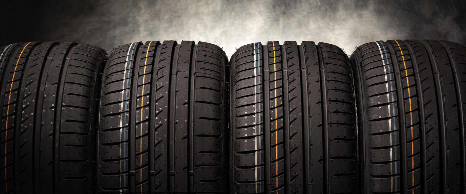 Four high-performance tires with distinct tread patterns and colored side markings, representing tire options available at Asher Auto Care for vehicle safety and performance in Dallas, TX.